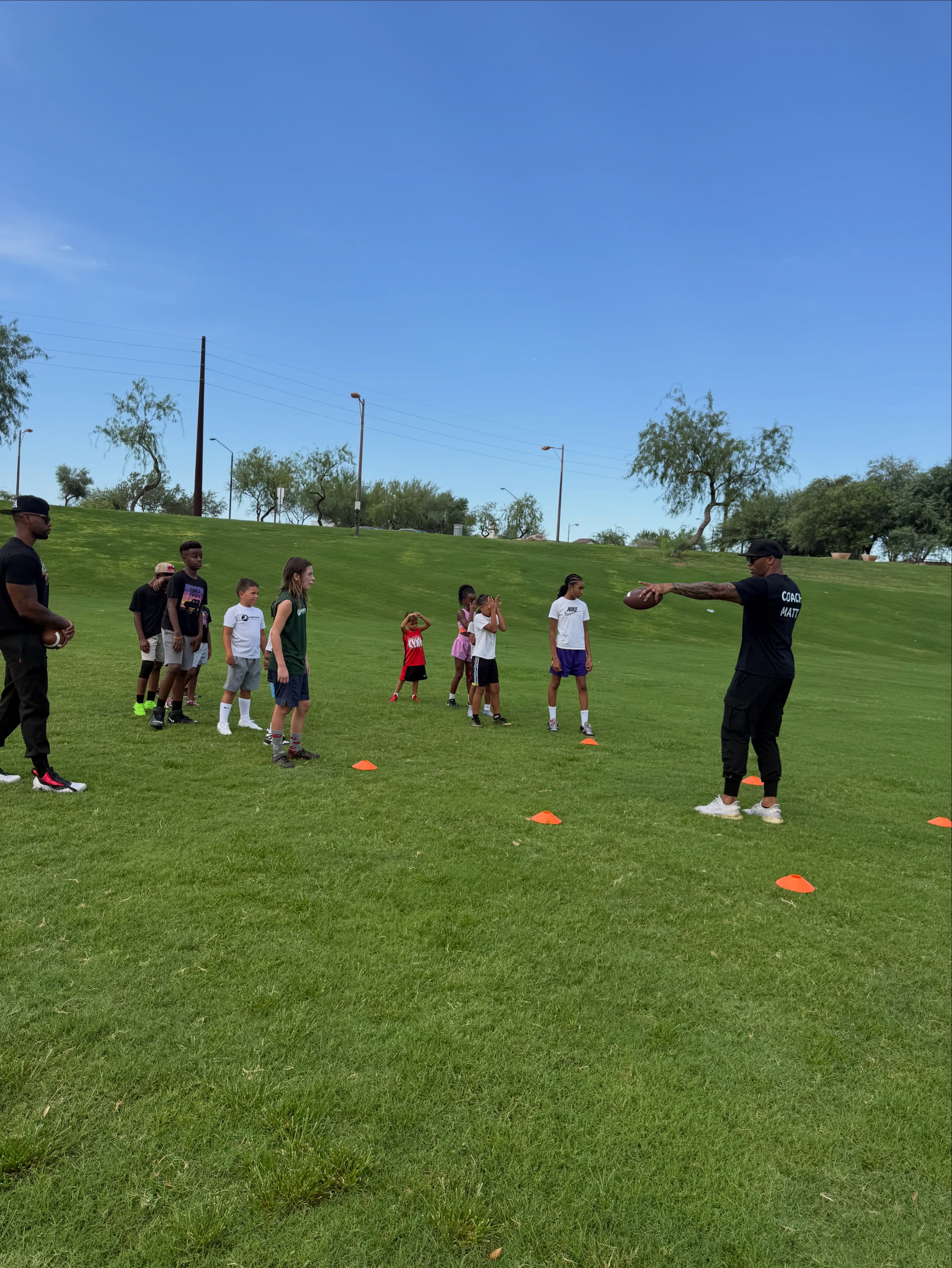 Coaches demonstrate a football drill to a group of Little Legends athletes.