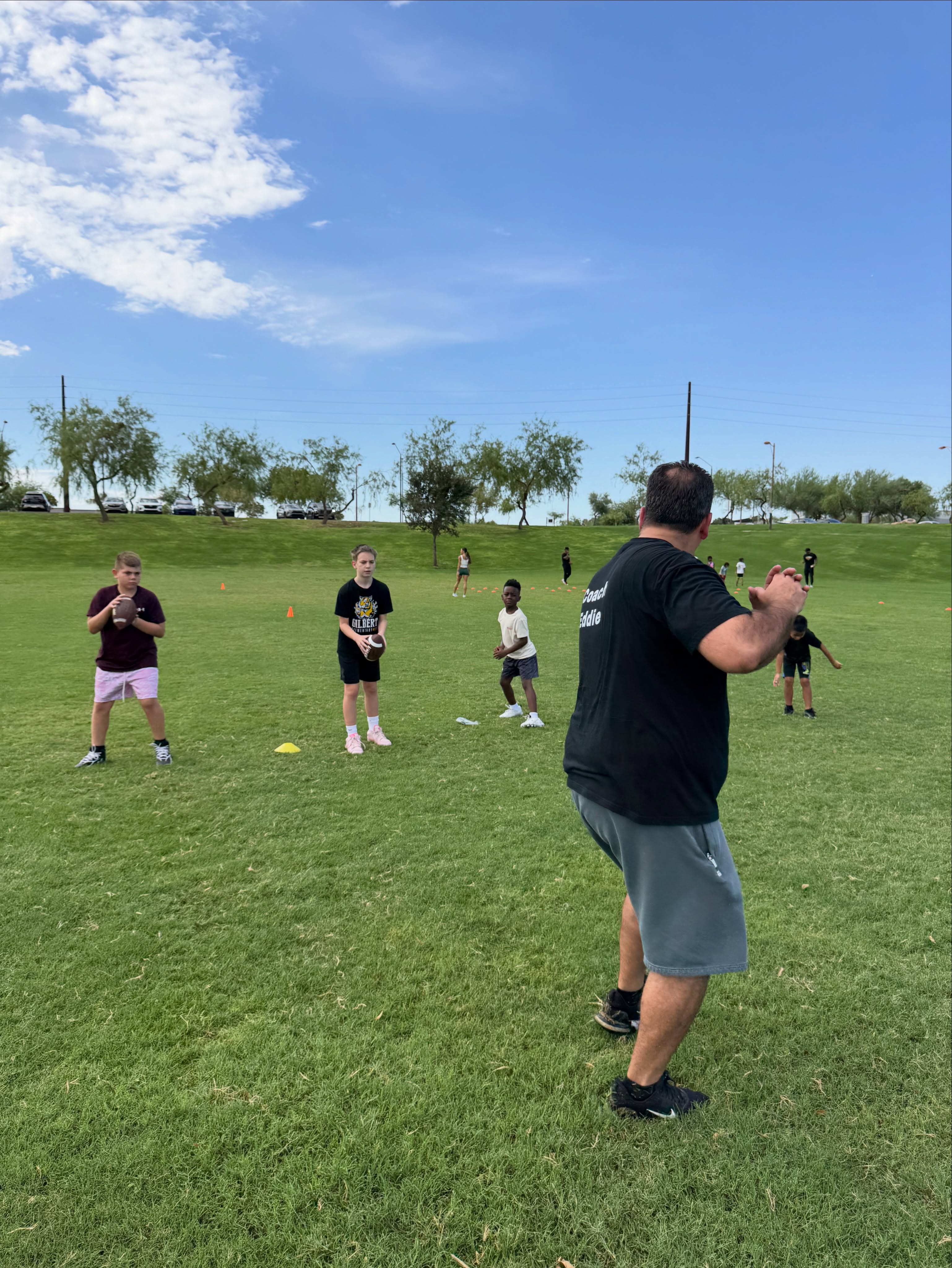 A coach guides athletes through throwing practice.
